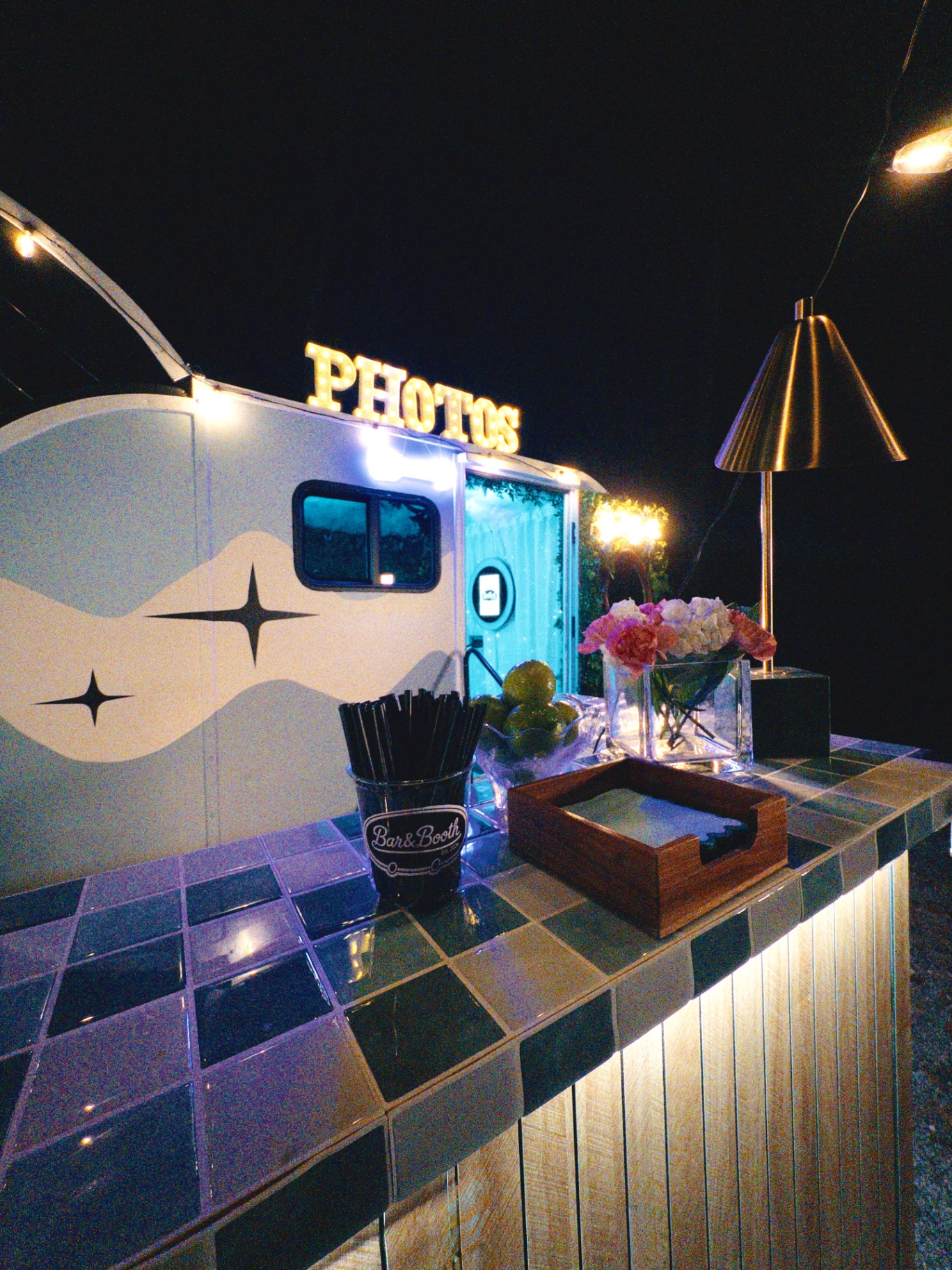 Tiled bar top with florals and PHOTOS marquee at night